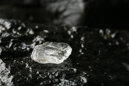 Shiny rough diamond on stone surface, closeup. Space for text