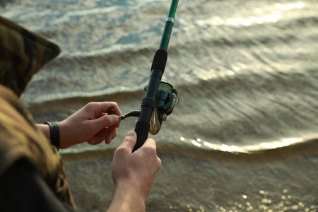 Fisherman with rod fishing at riverside, closeup. Space for text