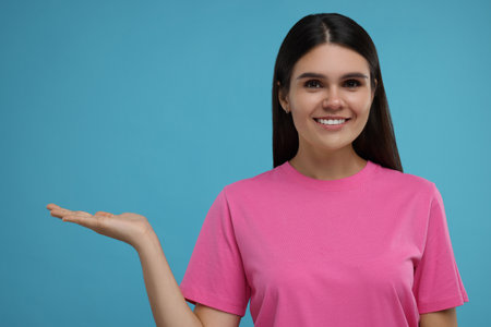 Special promotion. Happy woman holding something on light blue backgroundの写真素材