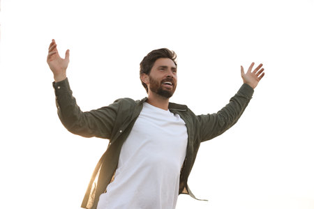 Feeling freedom. Happy man with wide open arms against sky outdoors, low angle view
