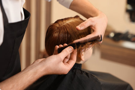 Professional hairdresser combing boy's hair in beauty salon, closeupの写真素材
