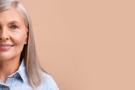 Portrait of beautiful middle aged woman on beige background, closeup. Space for text