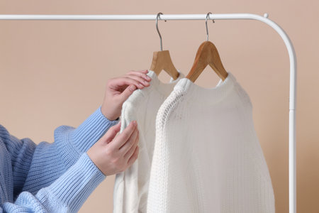 Woman sweat taking from rack on beige background, closeup