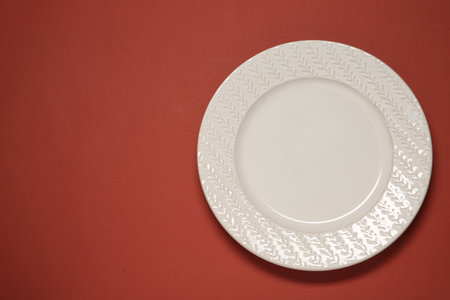 One white plate on red background, top view. Space for text