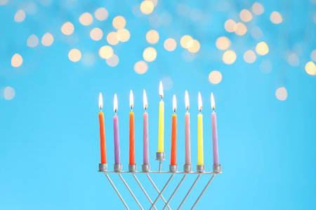 Hanukkah celebration. Menorah with burning candles on light blue background with blurred lightsの写真素材