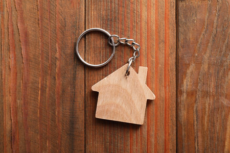One keychain in shape of house on wooden table, top viewの写真素材