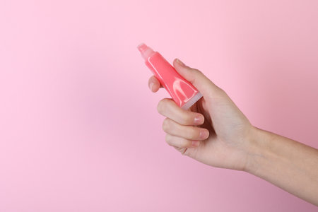 Woman with lip balm on pink background, closeupの写真素材