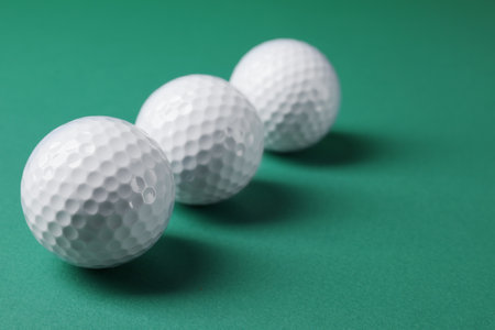 Three golf balls on green background, closeup. Space for textの写真素材