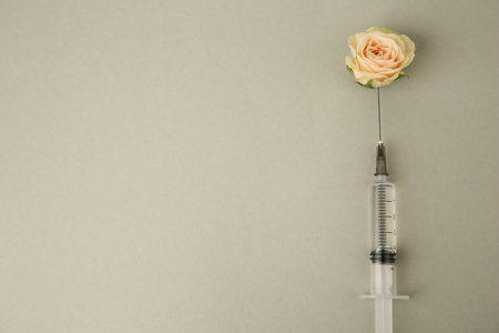 Medical syringe and rose flower on light gray background, flat lay. Space for text