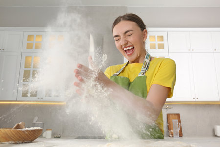 Funny woman clapping floury hands over messy table in kitchenの写真素材