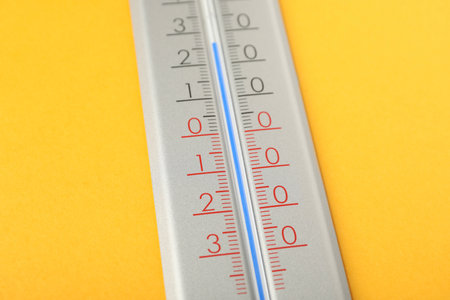 Modern weather thermometer on yellow background, closeup
