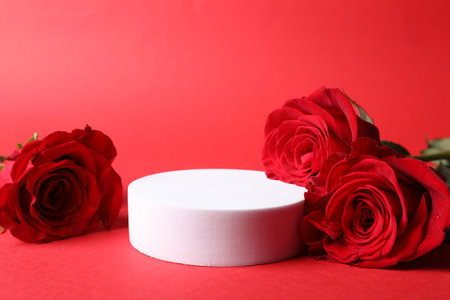 Stylish presentation for product. Round podium and beautiful roses on red background, space for textの写真素材
