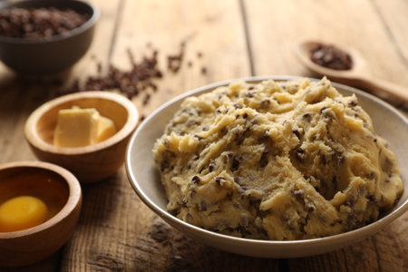 Chocolate chip cookie dough in bowl and ingredients on white wooden table, closeupの写真素材