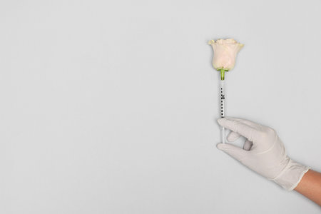 Doctor making injection to rose on light gray background, top view. Space for textの写真素材
