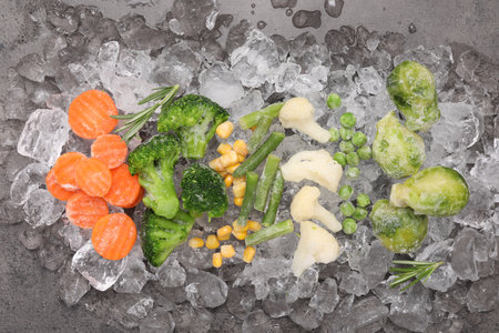 Different frozen vegetables with ice on gray table, flat layの写真素材
