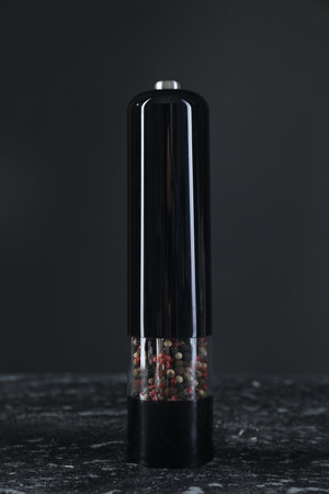 Pepper shaker on dark marble table, closeup