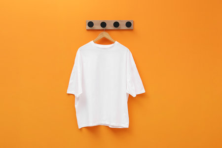 Hanger with white T-shirt on orange wallの写真素材