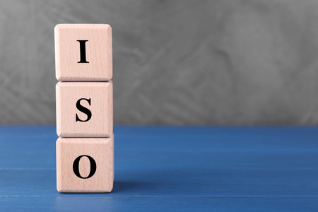 International Organization for Standardization. Cubes with abbreviation ISO on blue wooden table, space for textの写真素材