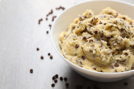 Chocolate chip cookie dough in bowl on light gray table, closeup. Space for textの写真素材