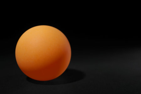 One ping pong ball on black background, space for textの写真素材