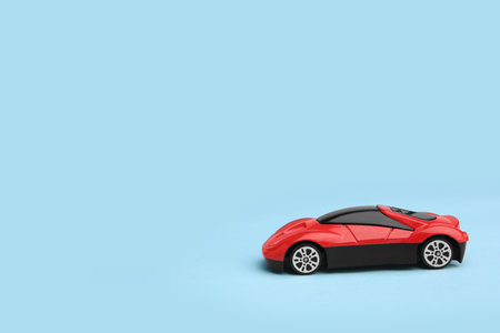 One red car on light blue background, space for text. Children's toy