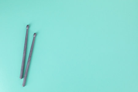 Two gray drumsticks on turquoise background, top view. Space for text