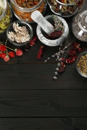 Mortar with pestle and many different herbs on wooden table, flat lay. Space for textの写真素材