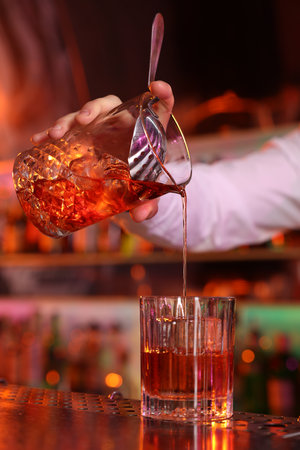 Bartender making fresh alcoholic cocktail at counter in bar, closeupの写真素材