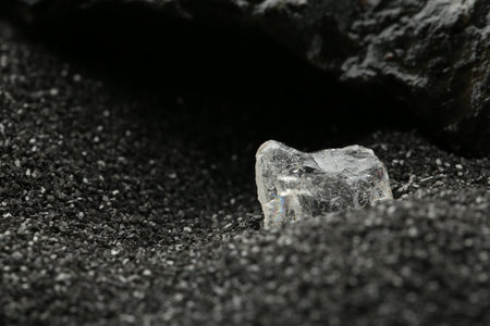 Shiny rough diamond on decorative black sand. Space for textの写真素材