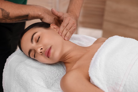Woman receiving professional neck massage on couch indoorsの写真素材