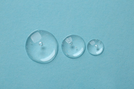 Drops of cosmetic serum on light blue background, top viewの写真素材