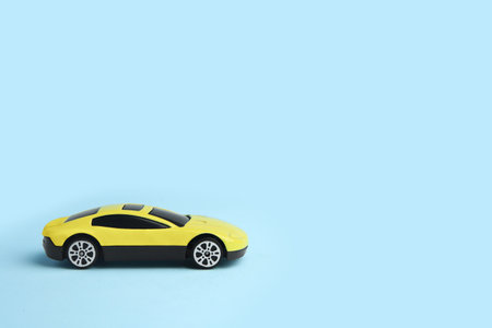 One yellow car on light blue background, space for text. Children's toy