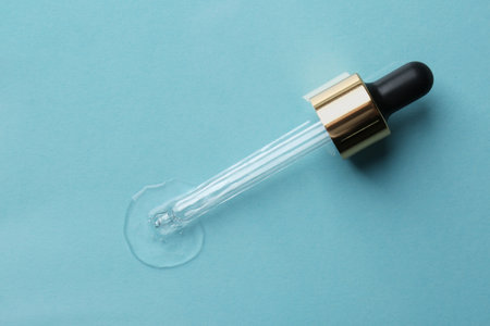Clear cosmetic serum and pipette on light blue background, top viewの写真素材