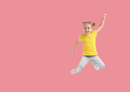 Cute girl jumping on pink background, space for textの写真素材