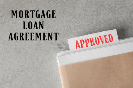 Mortgage loan agreement. Note with Approved stamp in documentation on light gray table, top viewの写真素材