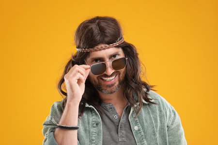 Stylish hippie man in sunglasses on orange backgroundの写真素材