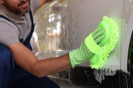 Worker in rubber gloves washing car with sponge, closeupの写真素材