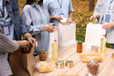 Volunteers packing food products at table in park, closeup