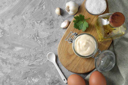 Tasty mayonnaise in jar and ingredients on gray textured table, flat lay. Space for textの写真素材