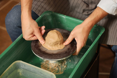 Man crafting with clay on potter's wheel, closeupの写真素材