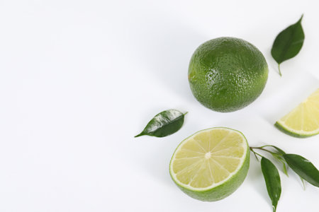 Fresh limes and leaves on white background, above view. Space for textの写真素材