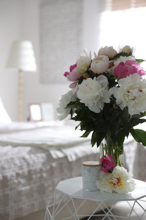 Beautiful blooming peonies on table in bedroomの写真素材
