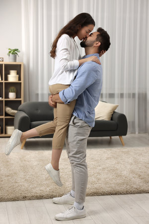 Love relationship. Passionate young couple kissing at homeの写真素材