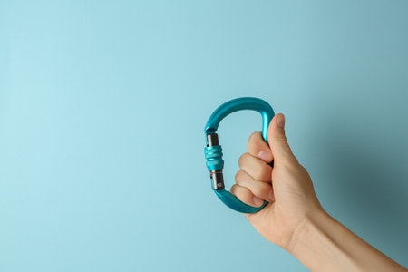 Woman with metal carabiner on light blue background, closeup. Space for textの写真素材