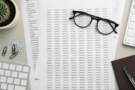 Accounting documents, glasses, computer keyboard and stationery on beige table, flat lay
