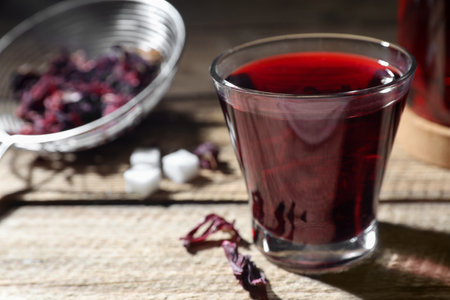 Delicious hibiscus tea in glass on wooden table, closeup. Space for textの写真素材