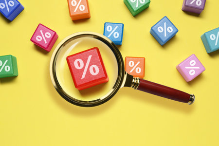 Best mortgage interest rate. Cube with percent sign on yellow background, view through magnifying...