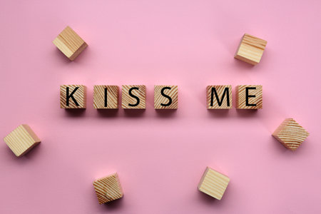 Wooden cubes with phrase Kiss Me on pink background, flat layの写真素材