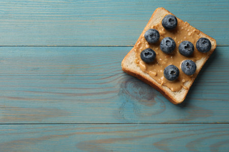Delicious toast with peanut butter and blueberries on light blue wooden table, top view. Space for textの写真素材