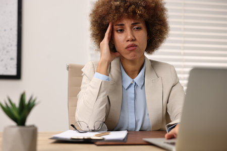 Woman suffering from headache at workplace in office